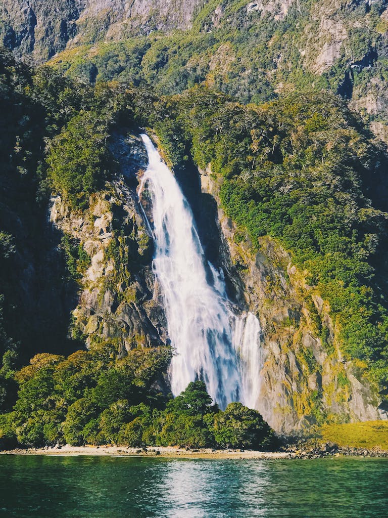 Beautiful waterfall cascading down lush green cliffs in Southland, New Zealand, captured in natural daylight.