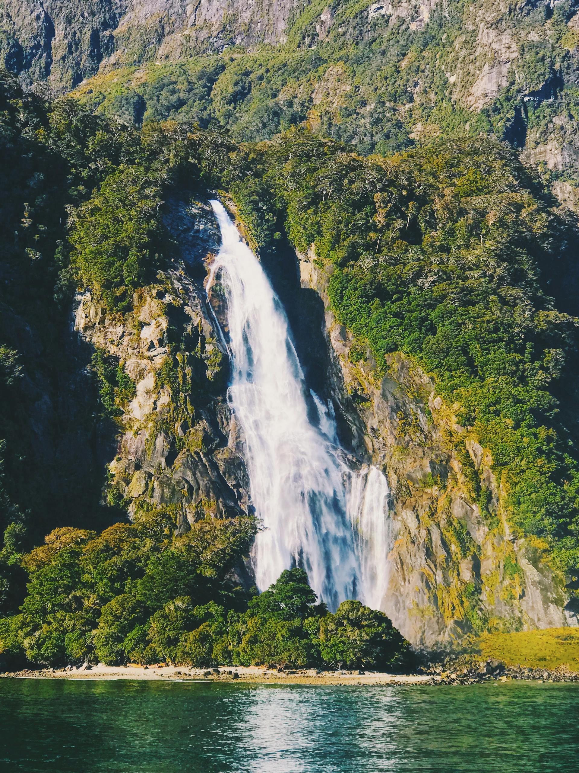 A waterfall cascading down green cliffs in Southland, New Zealand