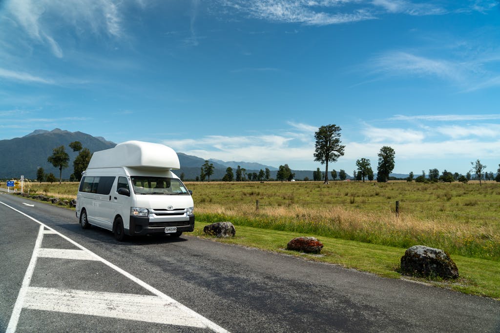 Campervan parked on a picturesque rural road under a clear blue sky.